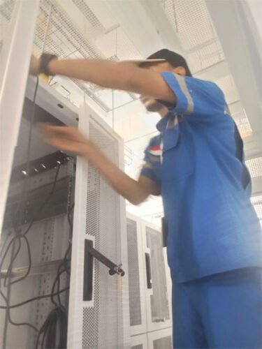 Teknisi Master CCTV sedang melakukan instalasi rack server dan penataan perangkat jaringan di ruang server Jakarta Timur.